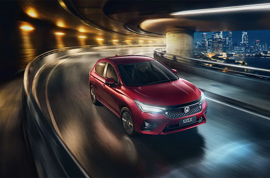 Honda City Hatchback vermelho em movimento, visto em três quartos dianteiro